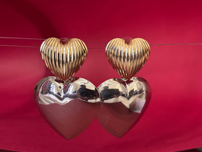 Heart-shaped earrings in gold and silver on a red background